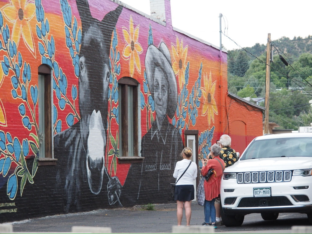 Mural on a building with people observing it.