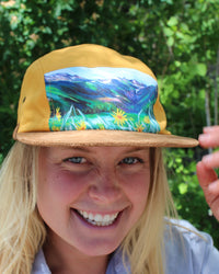 Person wearing a cap with a scenic design outdoors