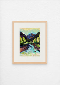 Framed painting of a mountain landscape with a river on a white wall