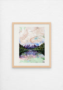 Framed artwork of a mountain landscape with a lake on a white wall