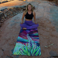Woman sitting on a colorful yoga mat outdoors