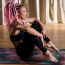 Woman with pink braids sitting on a yoga mat in a studio