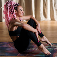 Woman with pink braids sitting on a yoga mat in a studio