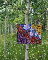 Colorful floral painting hanging on a tree branch in a forest setting