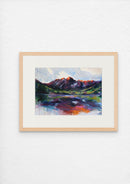 Framed painting of a mountain landscape with a lake on a white wall