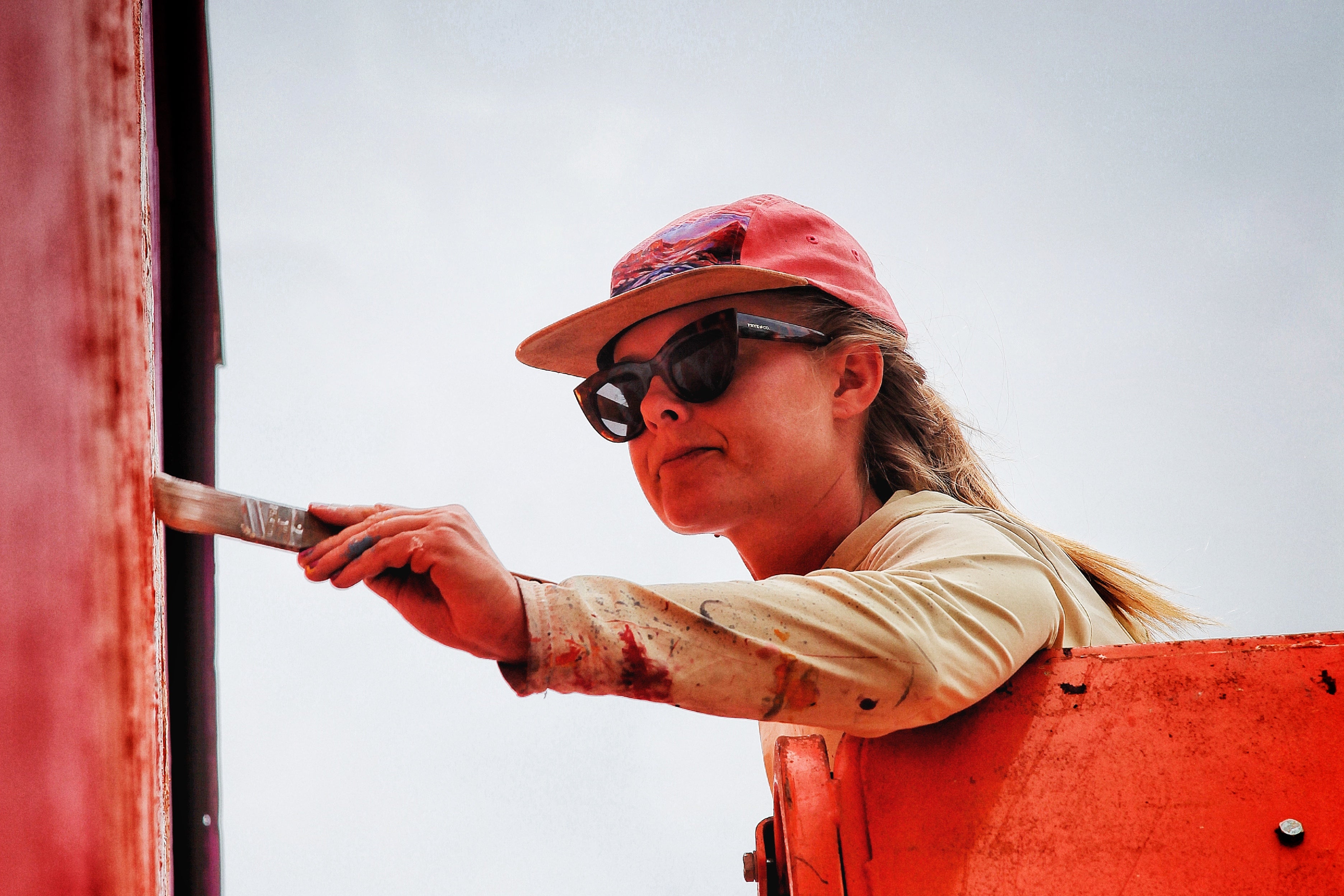 Person painting a red surface outdoors