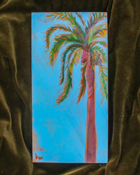 Painting of a palm tree on a blue background, set against a velvet blanket