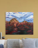 Painting of a desert mountain landscape on a yellow wall above a sofa.
